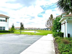 A parking lot with a fire hydrant, a sidewalk, and a building with a tiled roof. - 3 King Masters + Private Pool | 15 Min Disney (Kissimmee)