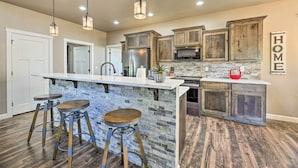 Una cocina con una isla de piedra, taburetes de madera y un letrero que dice 'HOME'.