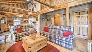A rustic cabin interior with plaid sofas, a wooden chest, and a loft with exposed beams. - Pet-Friendly New York Cabin w/ Hot Tub & Game Room (Maplecrest)
