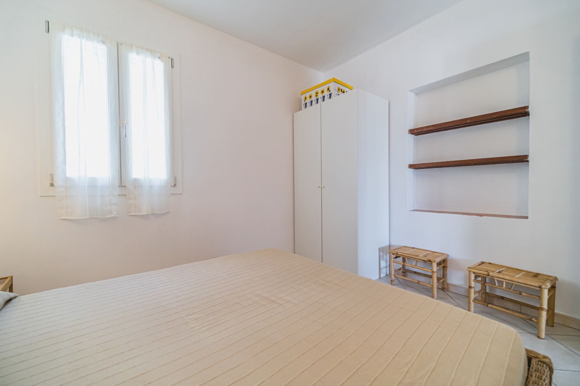 Un dormitorio con una cama, dos mesitas de madera, un armario y una estantería.