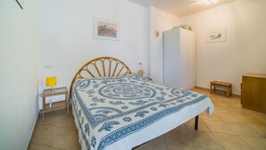 Um quarto com cama, mesa de cabeceira, luminária e guarda-roupa.