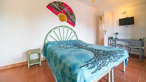 Une chambre à coucher comprenant un lit, un bureau, une chaise, un téléviseur et une petite table.