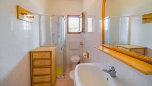 Une salle de bain avec douche, toilettes et lavabo.