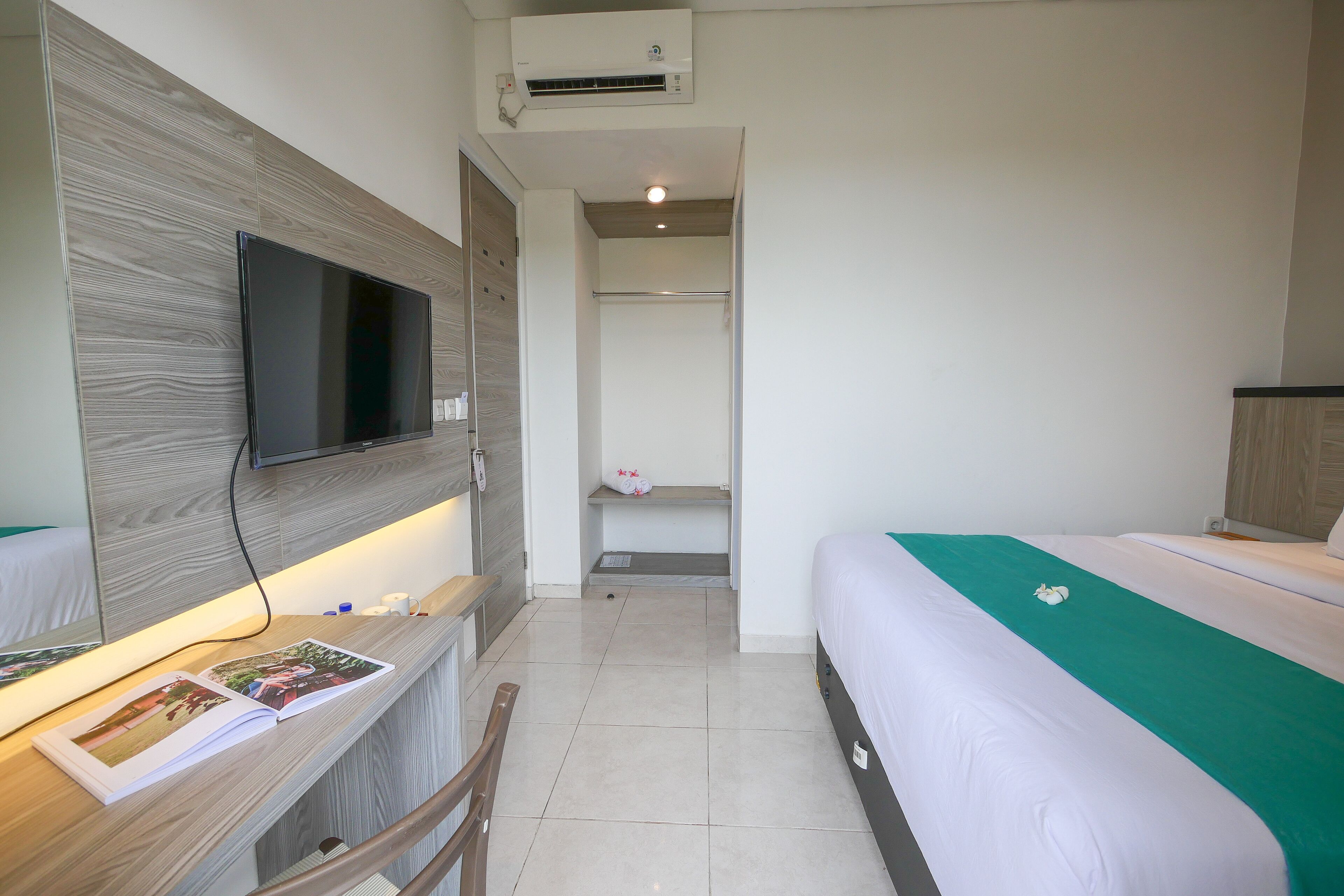 Een hotelkamer met een bed, een bureau met een flatscreen televisie, een spiegel en een plank met toiletartikelen.