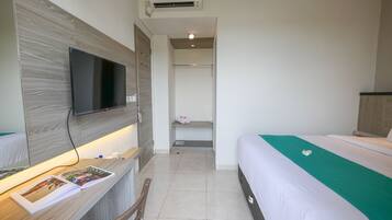 Een hotelkamer met een bed, een bureau met een flatscreen televisie, een spiegel en een plank met toiletartikelen.