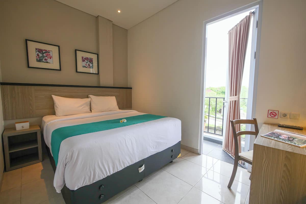 Een hotelkamer met een bed, een bureau, een stoel en een balkon met gordijnen.