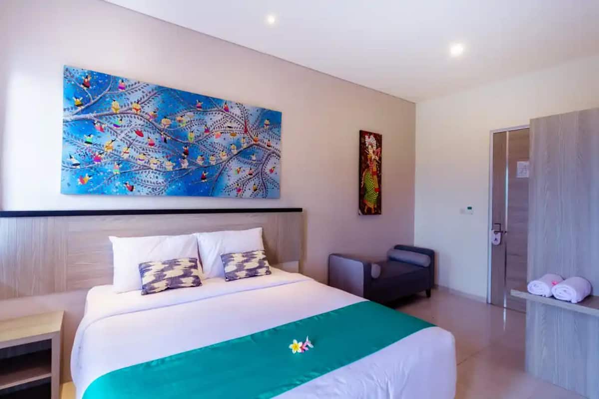 Een hotelkamer met een groot bed, een bureau, een stoel en een schilderij aan de muur.