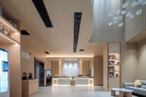 Un vestíbulo moderno de hotel con una recepción, zona de estar y un amplio ventanal.