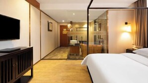 A hotel room with a bed, a TV, a desk, and a glass partition. - Mini Hotel (Huaihua)