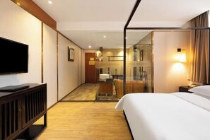 A hotel room with a bed, a TV, a desk, and a glass partition. - Mini Hotel (Huaihua)