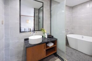 A modern bathroom with a large mirror, a round sink, a wooden cabinet, and a freestanding bathtub. - Mini Hotel (Huaihua)