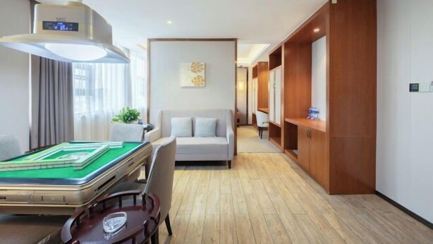 A hotel room with a pool table, a sofa, a wooden cabinet, and a ceiling fan. - Mini Hotel (Huaihua)