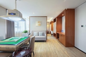 Habitación de hotel con mesa de billar, sofá, aparador de madera y ventilador de techo.
