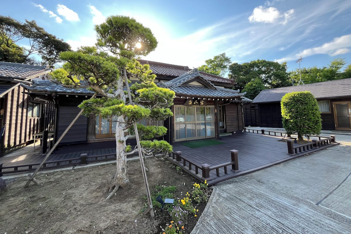 A traditional Japanese-style building with a wooden deck, surrounded by well-maintained gardens and trees.