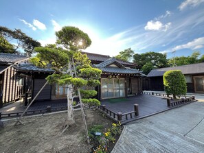 A traditional Japanese-style building with a wooden deck, surrounded by well-maintained gardens and trees. - One Night One View One Destiny Ichihara - Campsite (Ichihara)