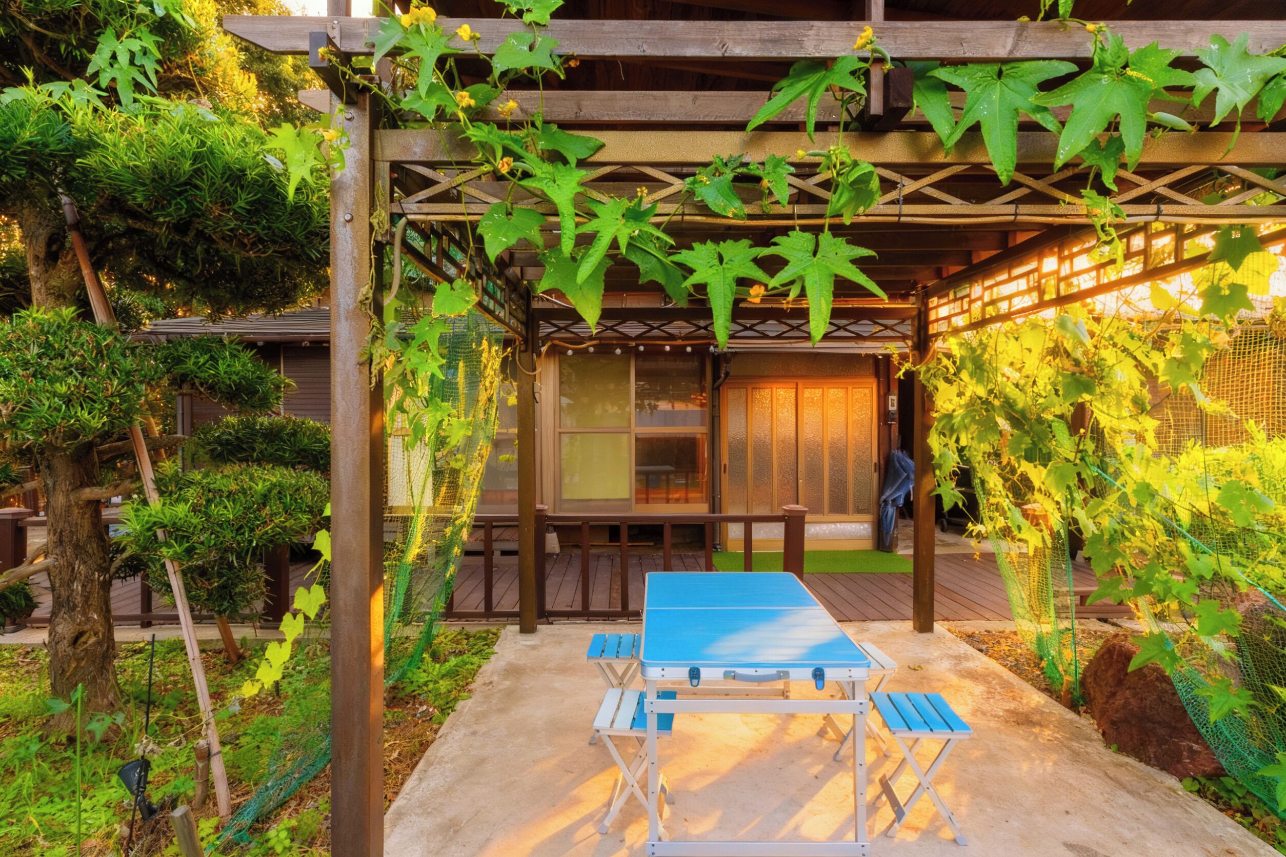 Un espacio al aire libre cubierto con mesa de ping pong, terraza de madera y abundante vegetación.