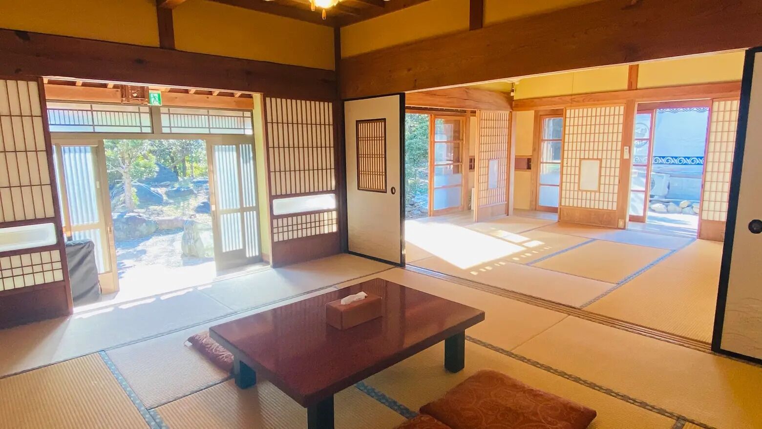 A traditional Japanese room with tatami flooring, sliding doors, and a small table with a tissue box.
