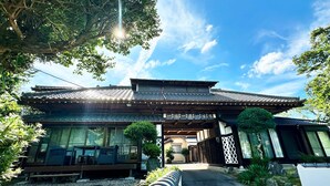 Un edificio japonés tradicional con techo de tejas, una puerta de madera y un camino que lleva a la entrada.