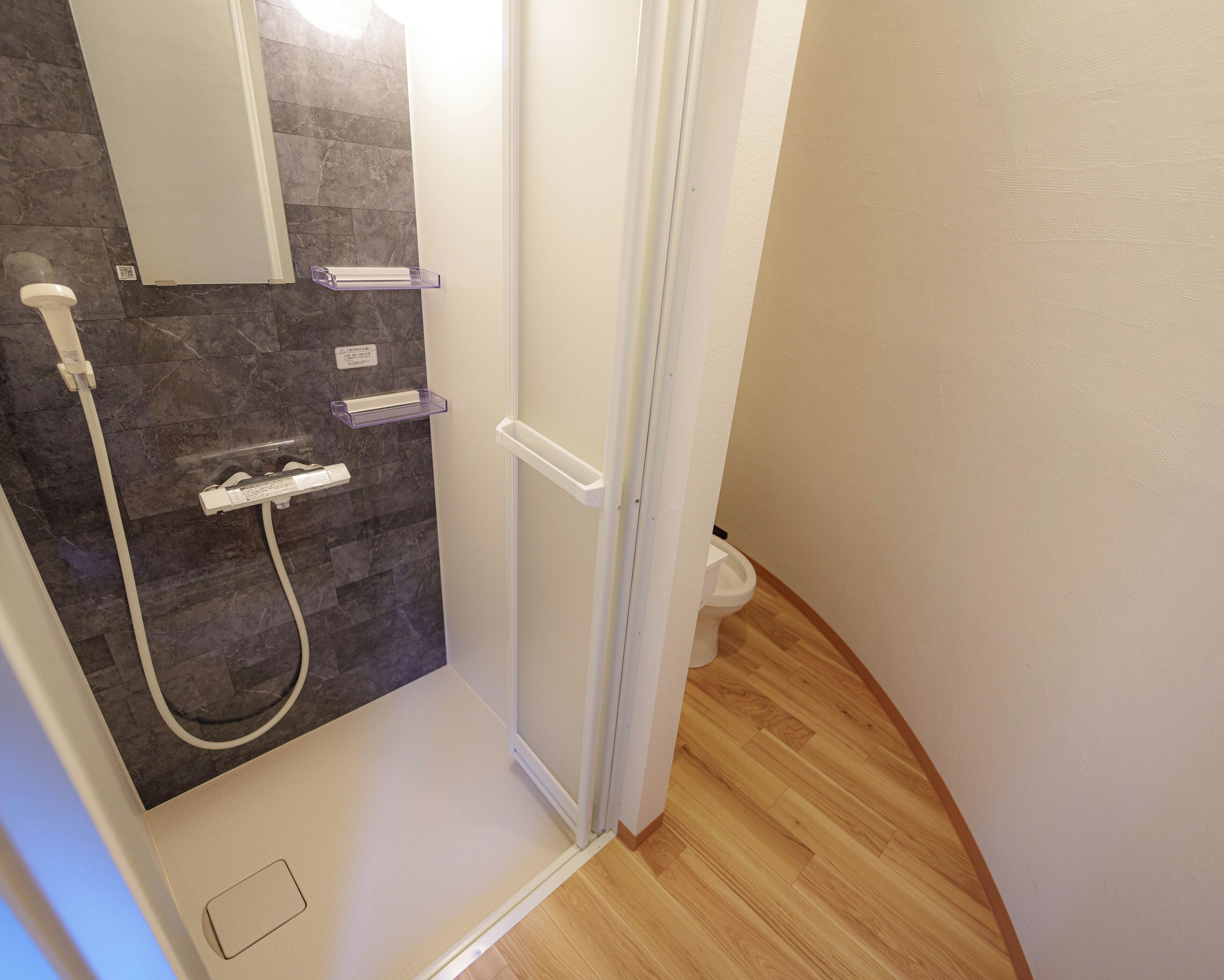 A bathroom with a shower, a toilet, and a mirror.
