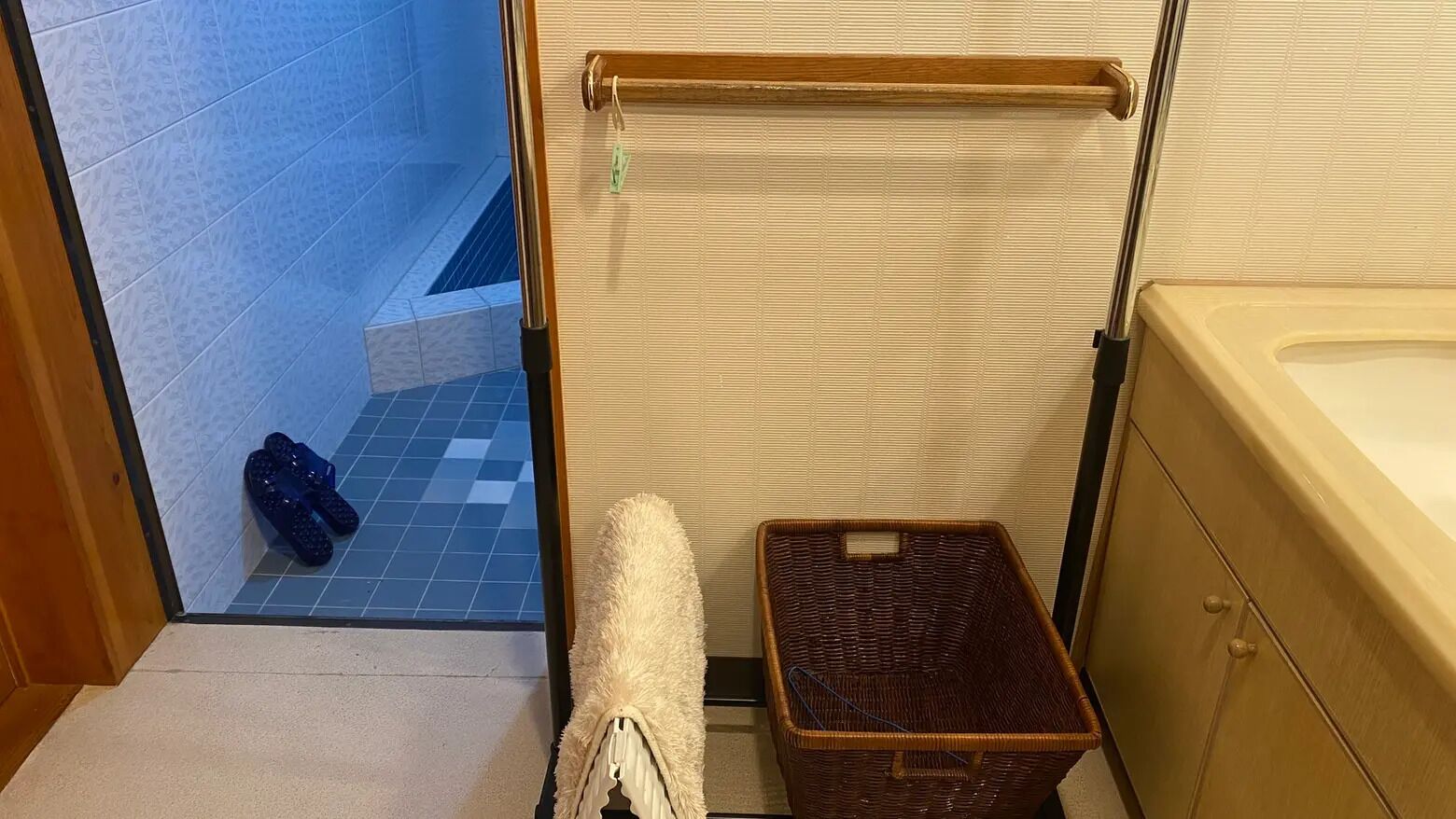 A bathroom with a bathtub, a wicker basket, and a towel on the floor.