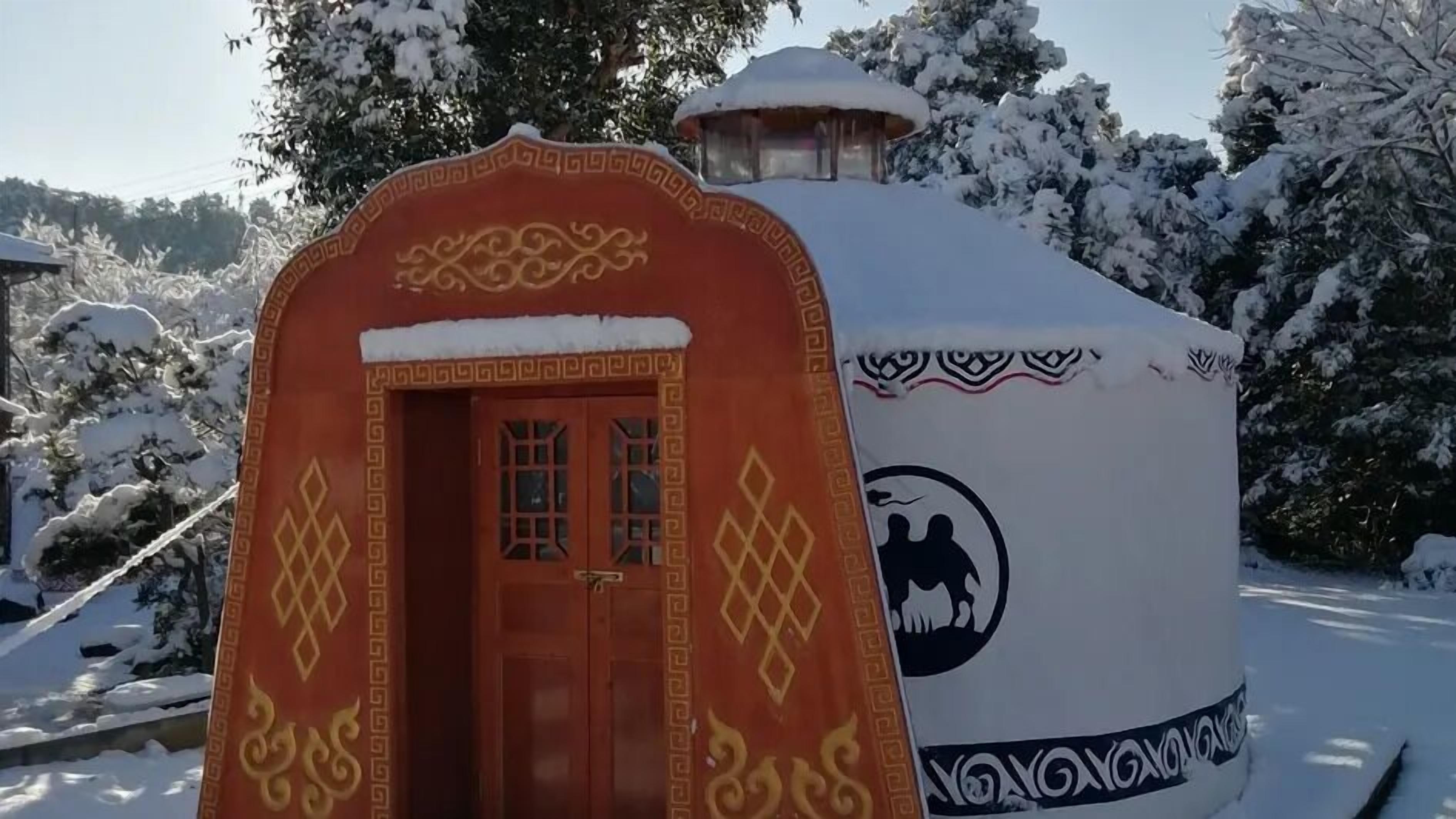 Un edificio imbiancato dalla neve con una facciata caratteristica rossa e bianca, dotato di una porta e finestre.