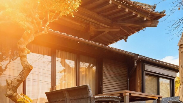 Una casa tradicional japonesa con suelo de tatami, una terraza de madera y vistas al jardín circundante.