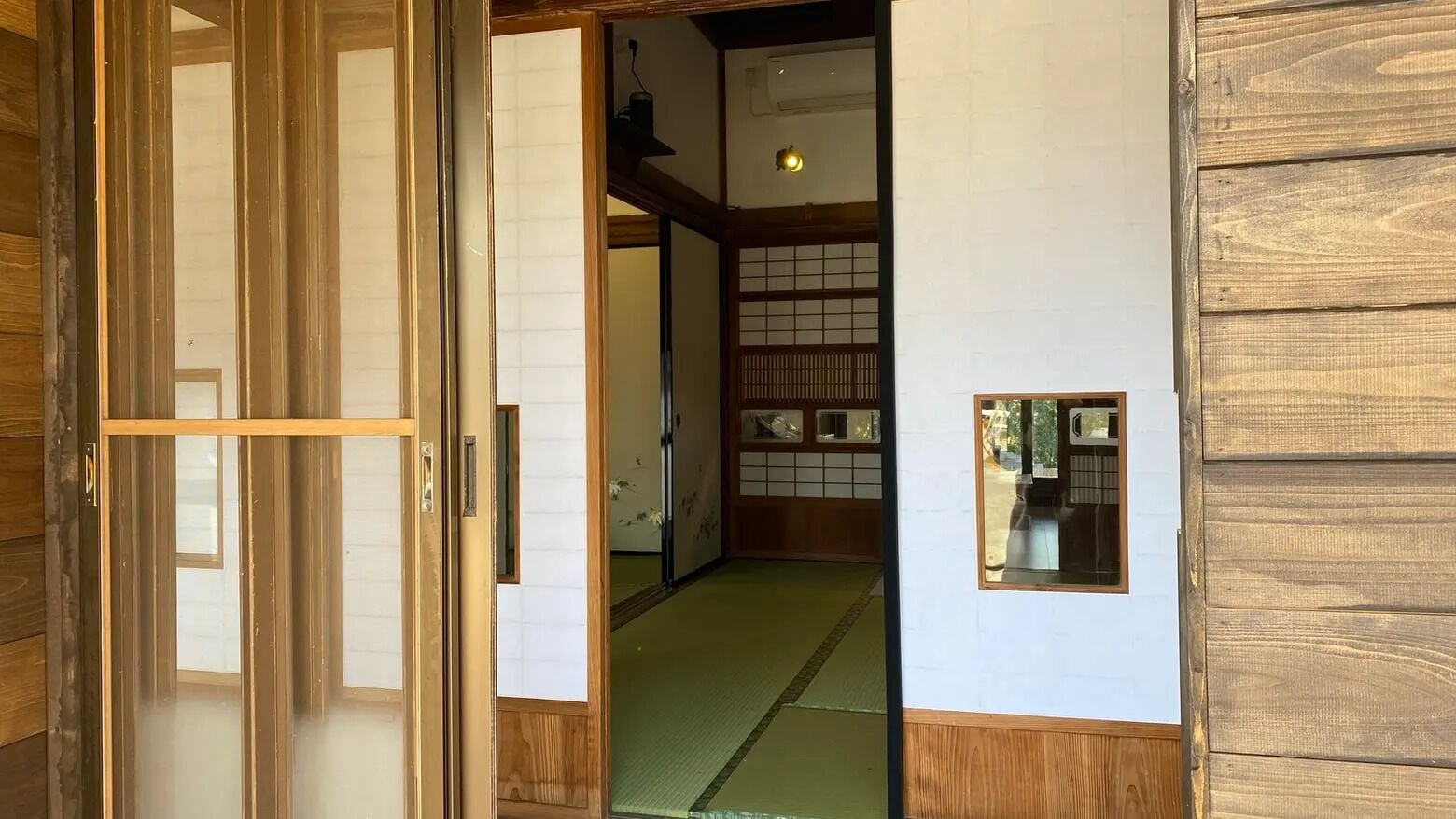 Un intérieur japonais traditionnel avec un sol recouvert de tatamis, des portes coulissantes et des lambris en bois.
