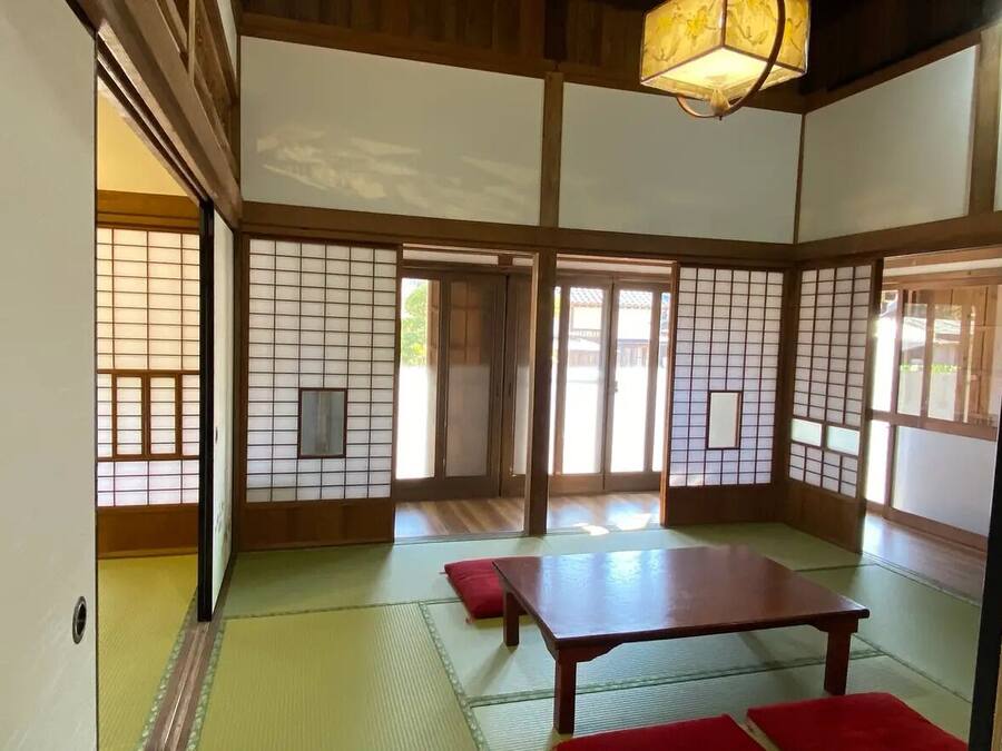 Una habitación japonesa tradicional con suelo de tatami, puertas correderas y una mesa de madera baja.