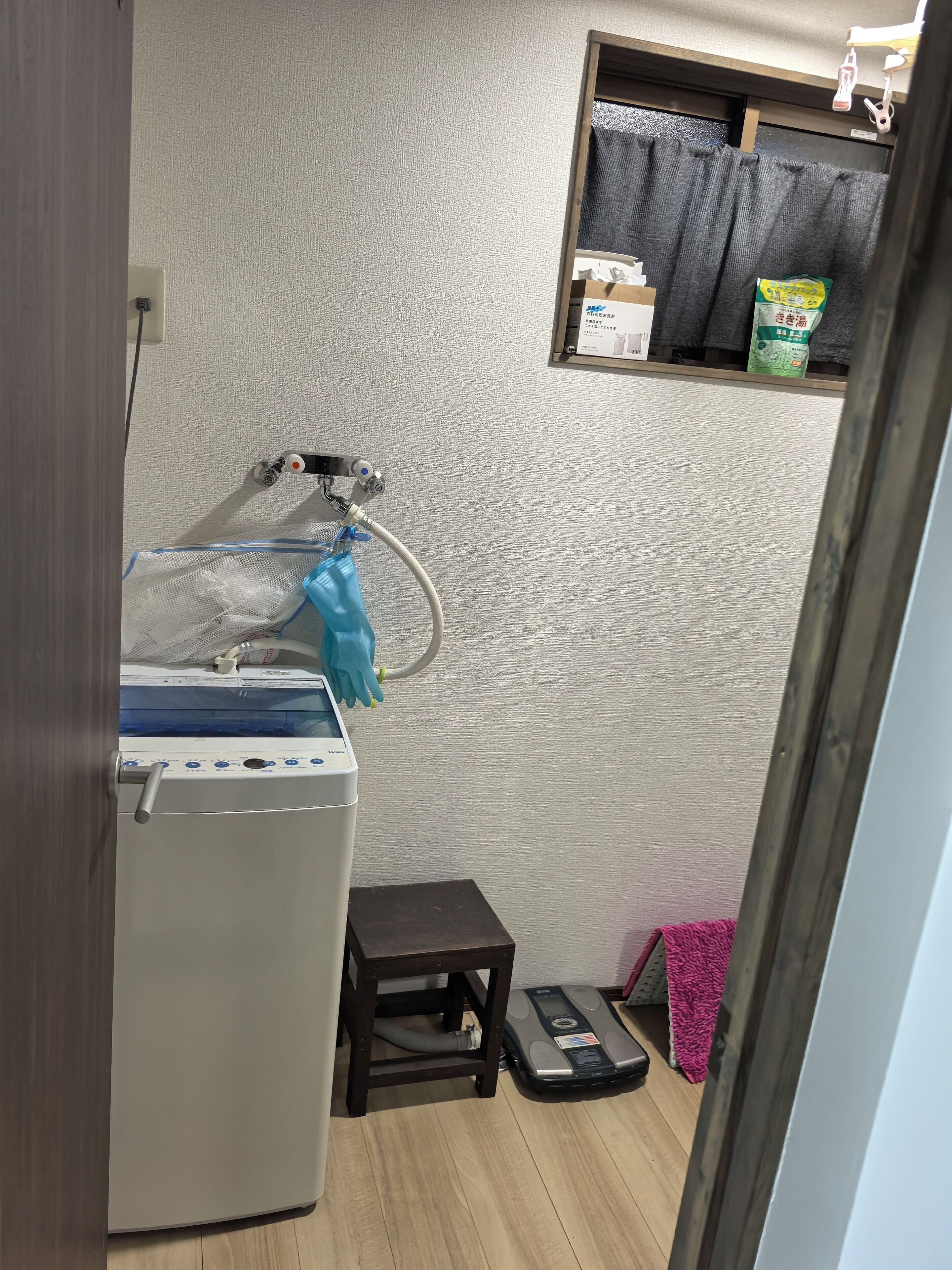 Une petite buanderie équipée d’un lave-linge, d’un petit tabouret et d’un aspirateur.