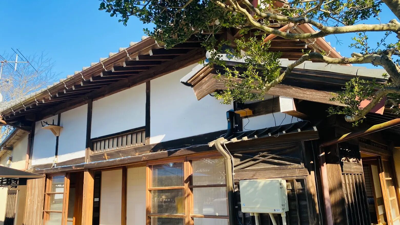 A traditional Japanese building with a wooden structure, large windows, and a visible air conditioning unit.