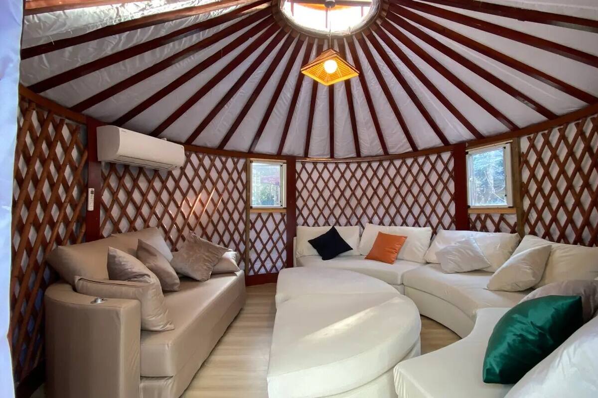 A yurt interior with a central seating area, a ceiling fan, and two windows.