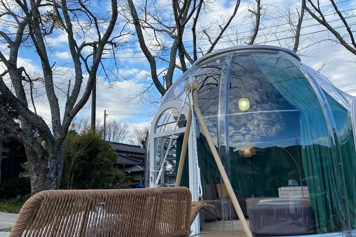 A transparent dome structure with a wicker chair in front.