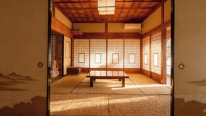 Una habitación japonesa tradicional con suelo de tatami, puertas correderas y bajo techo de madera.