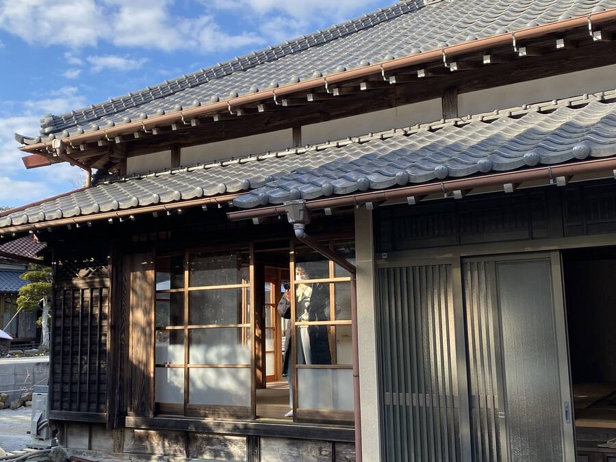 A traditional Japanese building with a tiled roof, wooden beams, and sliding doors.