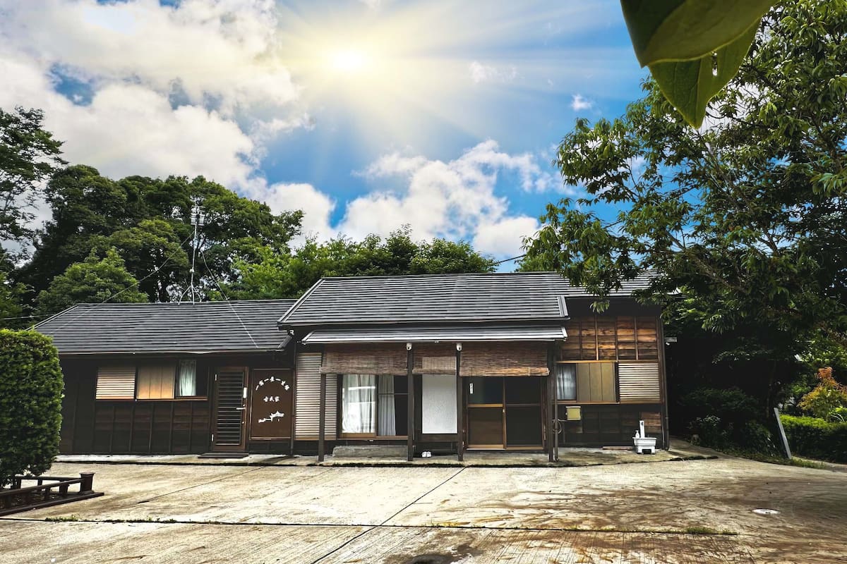 A traditional Japanese-style building with a tiled roof, wooden walls, and a small front garden.