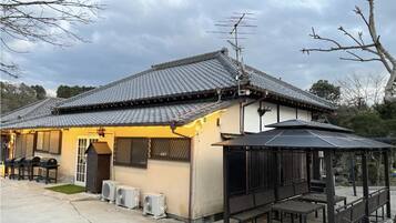 A traditional Japanese-style building with a tiled roof, a small porch with benches, and a covered seating area.
