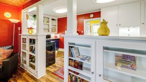 A room with a red wall, white cabinets, and a yellow vase on a counter. - Homey Cottage with Sunroom & Smart TV! (Highland)