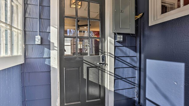 A dark blue exterior door with a glass panel, a metal door handle, and a small step leading to the entrance. - Homey Cottage with Sunroom & Smart TV! (Highland)