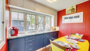 A kitchen with a window, a dining table with chairs, and a red wall. - Homey Cottage with Sunroom & Smart TV! (Highland)