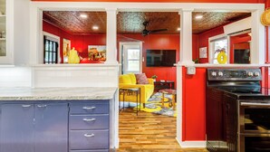 A kitchen with a red wall, a yellow sofa, and a black oven. - Homey Cottage with Sunroom & Smart TV! (Highland)