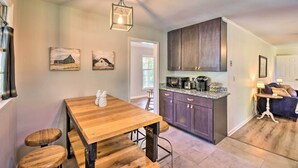 A kitchen with wooden bar stools, a wooden table, and a hanging light fixture. - Mod 'Stable House' on 10 Acres, Walk to Lake! (Oakwood)