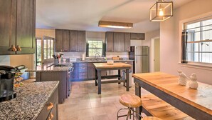 A modern kitchen with dark wood cabinets, granite countertops, and a central island. - Mod 'Stable House' on 10 Acres, Walk to Lake! (Oakwood)