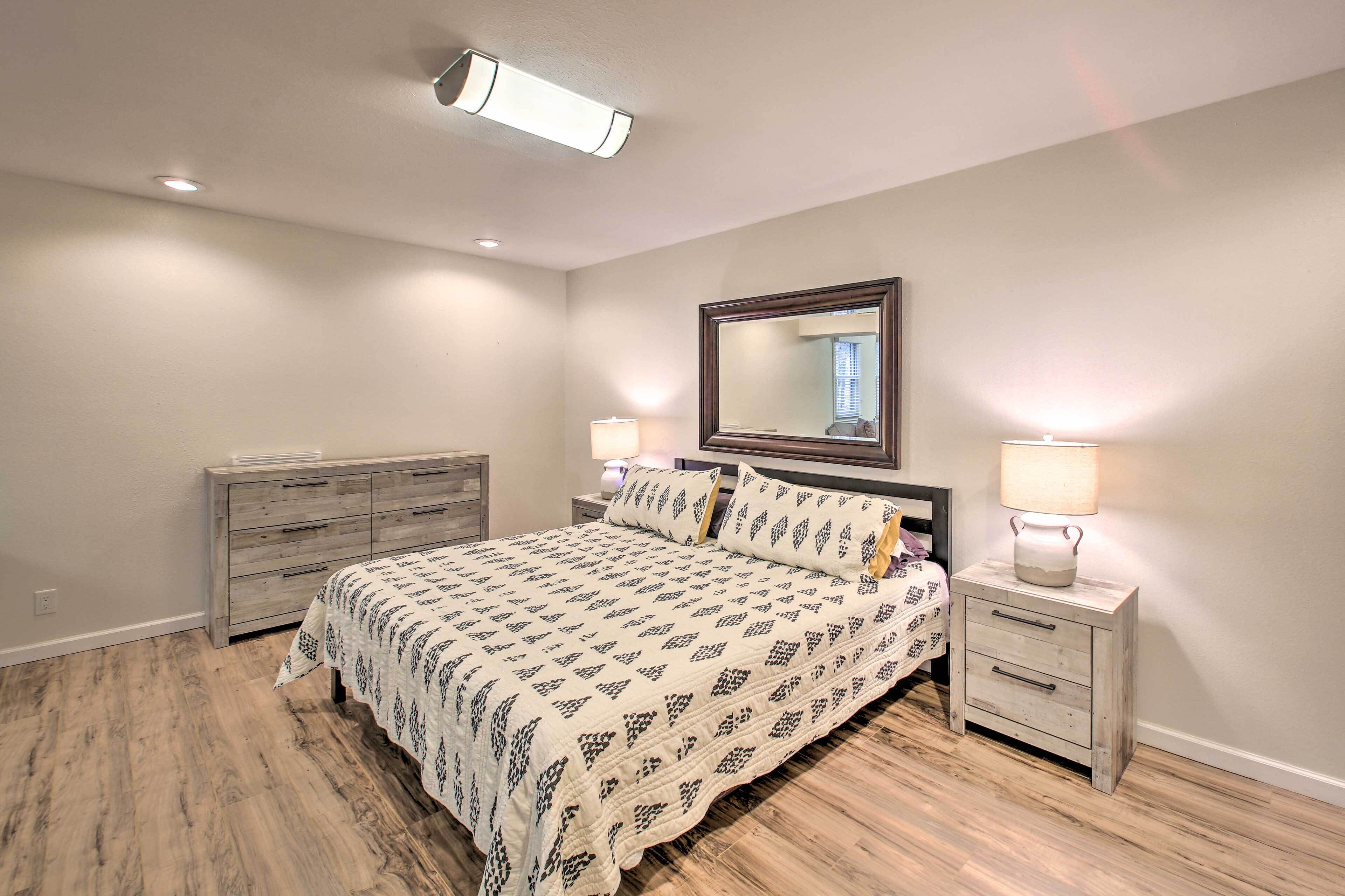Un dormitorio con cama, mesitas de noche, cómoda y espejo.