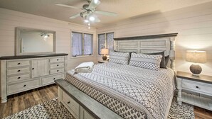 Een slaapkamer met een bed, nachtkastjes, een dressoir, een plafondventilator en een raam.