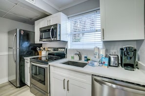 A modern kitchen with stainless steel appliances, a microwave, a coffee maker, and a sink.