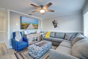 A living room with a ceiling fan, a sofa, a chair, and a rug.