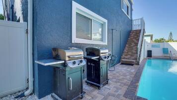 Ein Garten mit Schwimmbad, zwei Grillanlagen und einer Treppe zu einer Terrasse.
