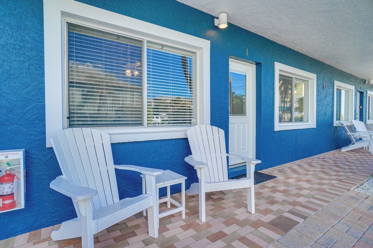 Un espace extérieur abrité, aménagé avec des chaises Adirondack blanches et un sol à carreaux.