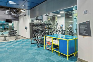 A gym with exercise equipment, a wall-mounted sign, and a blue and yellow storage unit. - Aloft by Marriott Anchorage (Anchorage)