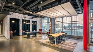 A modern indoor space with a pool table, billiards, and a dining area with chairs and a table. - Aloft by Marriott Anchorage (Anchorage)